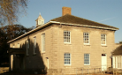 Photograph of the facade of a two-storey brick building with casement windows