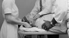 A patient is shown being strapped into an electroshock therapy table.