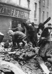 Kids climb rubble and collect scraps in front of a seized manufacturing property